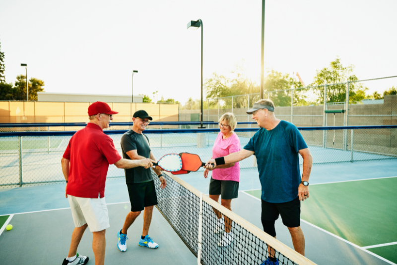 Group of 4 friends celebrating the end of a game of pickleball